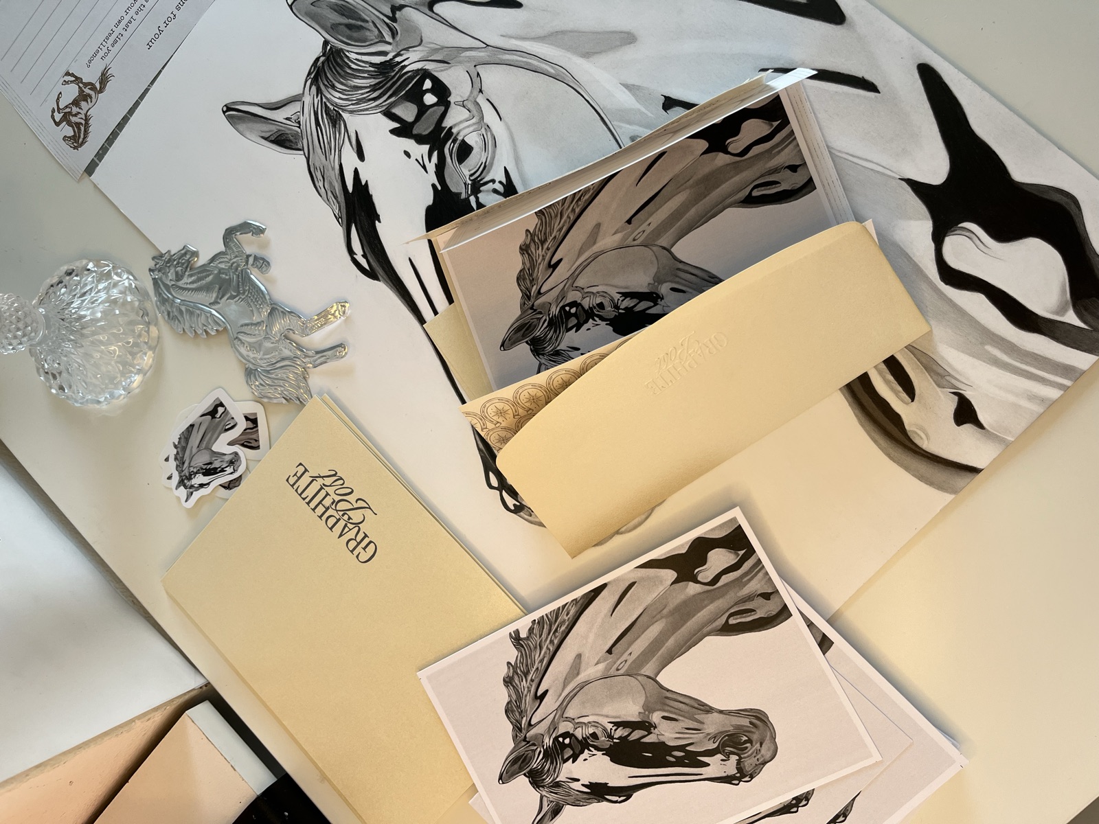 Graphite Post horse art prints and package contents on studio desk overhead view