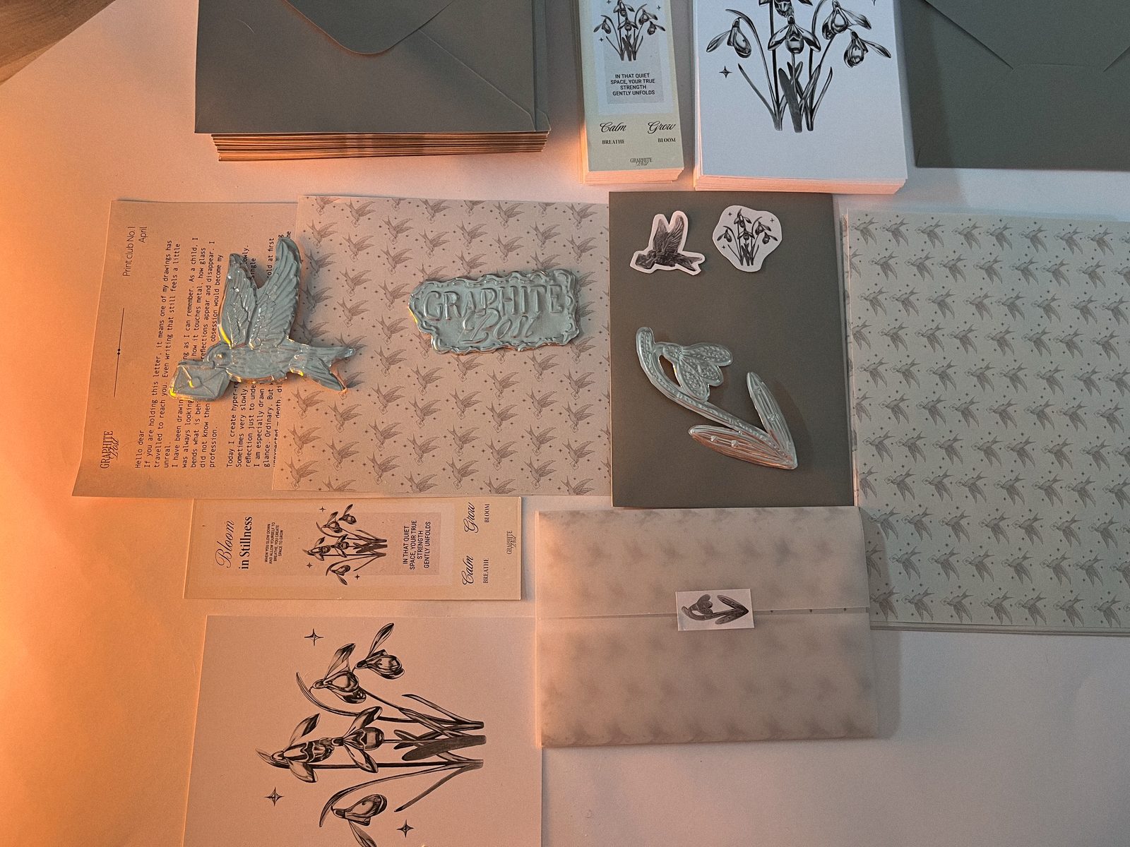 Snowdrop collection, everything in the envelope laid out: print, bookmark, letter, stickers and embossed foil pieces