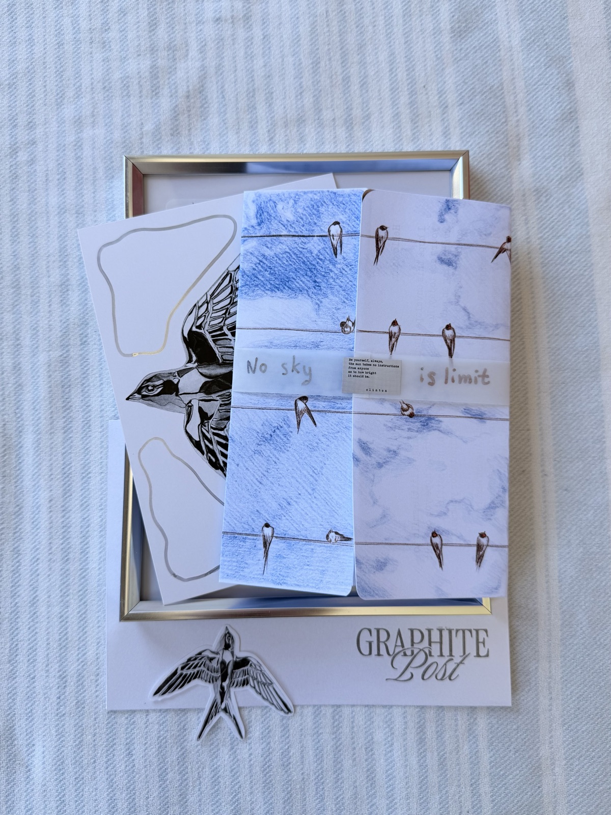 Graphite Post swallow collection — framed swallow print, sticker sheet and envelope on striped linen